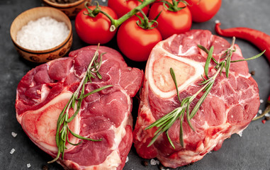 two raw beef steaks with tomatoes and spices on a concrete background with copy .Close-up .Cooking dinner concept for two