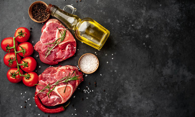 two raw beef steaks with tomatoes and spices on a concrete background with copy space for your text. Concept of cooking dinner for two