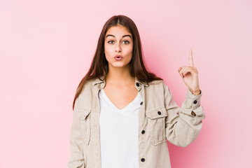 Young caucasian woman posing in a pink background having some great idea, concept of creativity.