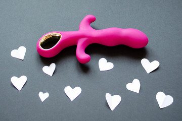 Obraz premium Sex toy. Pink vibrator on a black background with hearts. Useful for sex shop