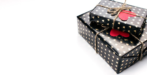 Gift boxes wrapped in black paper with hearts flat lay on white background with copy space. 8 march, Mother's day, Valentine's Day gifts top view. Celebrate concept. Template for web. Stock photo.