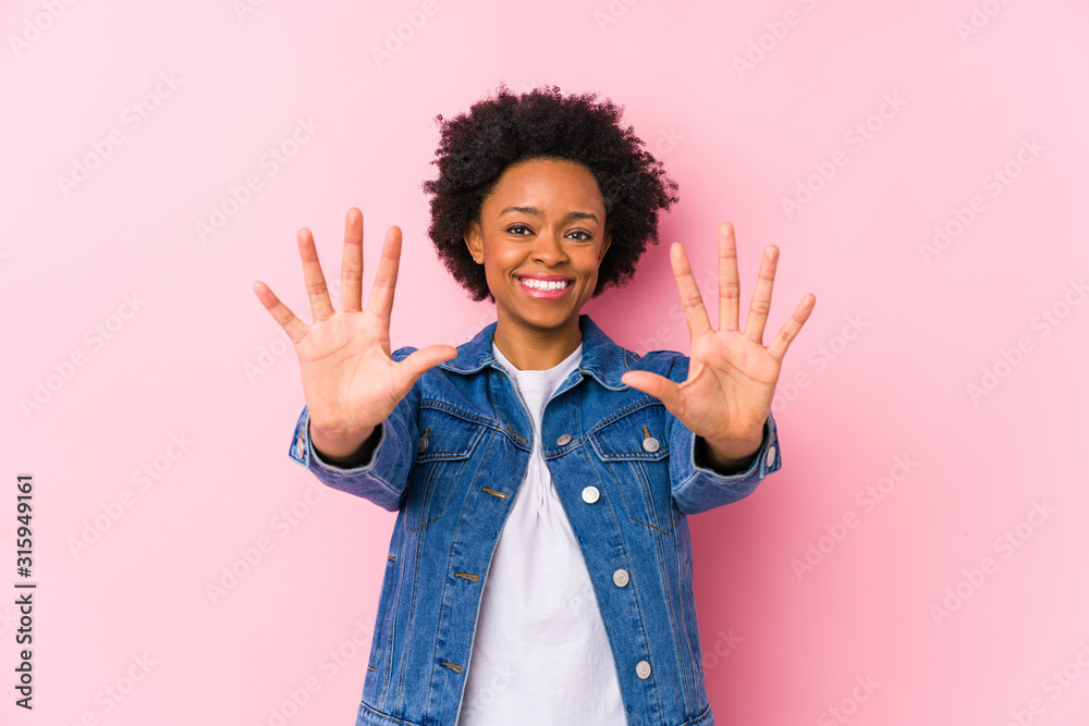 Wall mural young african american woman against a pink backgroound isolated showing number ten with hands.