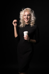 Laughing curly girl with cup of coffee isolated on black background