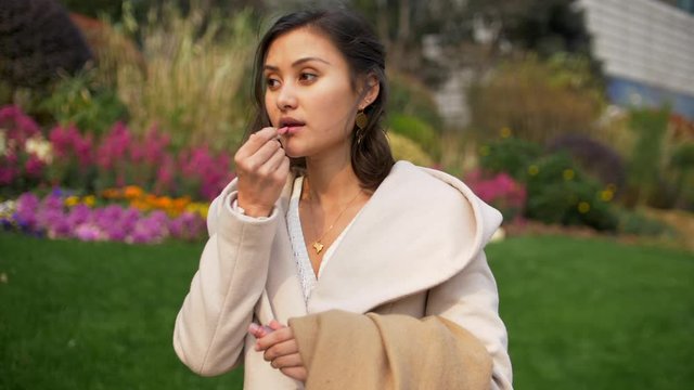 Beautiful Mixed Young Woman Puts on Lipstick Slow Motion Outside 