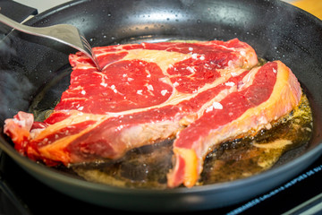 Cooking a big steak on a black pan