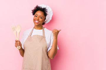 Young african american cook woman points with thumb finger away, laughing and carefree. - Powered by Adobe