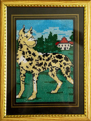 Embroidered Dalmatian. Dog on green grass in the background of the house. Cross-stitch.