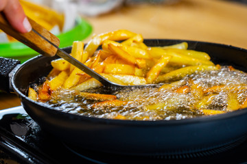 Frying a lot of french fries on a black pan