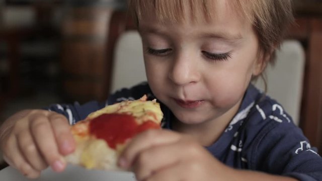 Close up of little cute boy eating pizza. Neutral colors for collor correction.