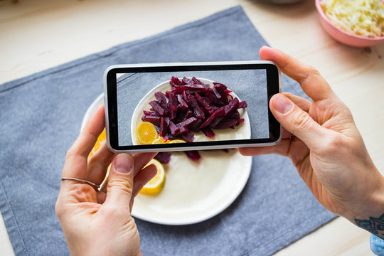 Hands make photo of food with smartphone. Phone photography of beet salad for blogging in trendy social media style