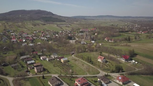 Cieklin, Poland - 7 7 2019: Roman Catholic Church in the center of a picturesque village located on green hills. Aerial drone or quadrocopter aerial view. European farms. Private Farm Panorama