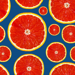 Fresh red orange or grapefruit on a blue classic background. Beautiful cut juicy slices. Pattern seamless tropical fruit photo.