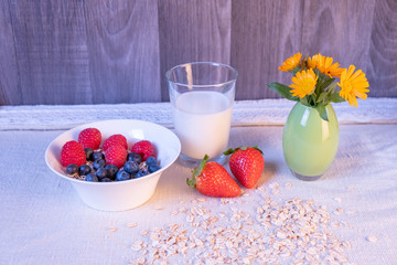 berries in a cup and milk in a glass on the table