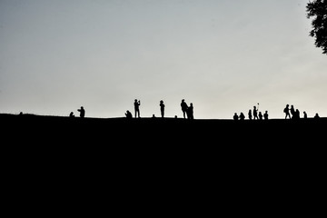 Naklejka na ściany i meble Silhouette of many people standing on the hill