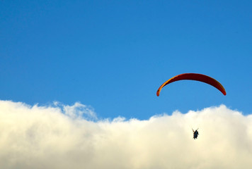 Paraglider flying against blue sky with clouds in south Tenerife,Canary Islands,Spain.Paragliding.Concept of extreme sport activity.Selective focus.