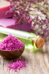 Sea salt in bowl, aroma oil in bottles, Wellness and flowers on grey textured background and flowers on vintage wooden background. Selective focus.