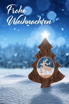Frohe Weihnachten Karte mit Weihnachtsbaum im Schnee und Schneeflocken vor einem Wald in der Farbe blau