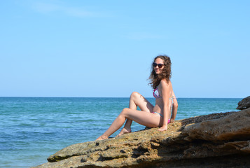 Young woman in a swimsuit and sunglasses on the seashore