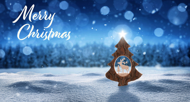 Weihnachtskarte mit Weihnachtsbaum mit Stern im Schnee und Schneeflocken vor einem Wald in der Farbe blau