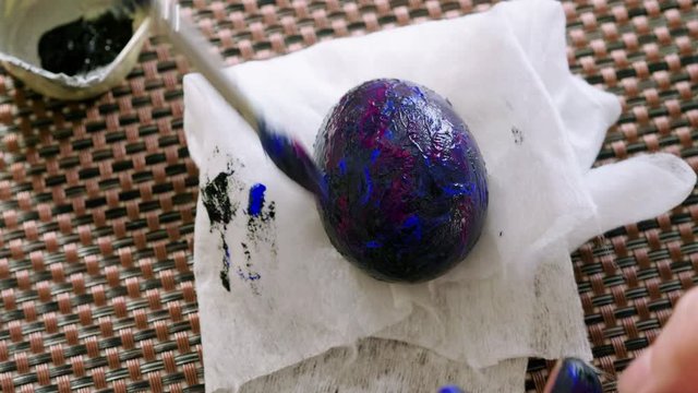 Preparation for Easter Day. Close up of women's hands coloring easter egg with paint and brush. 4K