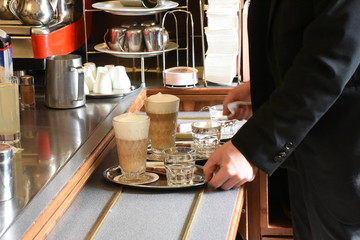 Fototapeta na wymiar A waiter prepares to serve coffee topped with cream inside a Vienna cafe