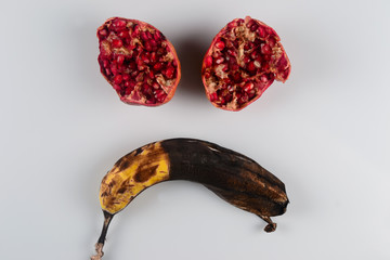 Ugly food: banana and pomegranate on white background