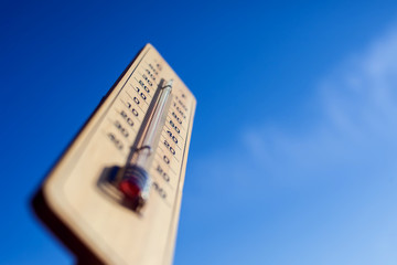 Thermometer on the blue sky background. Weather forecast and temperature concept
