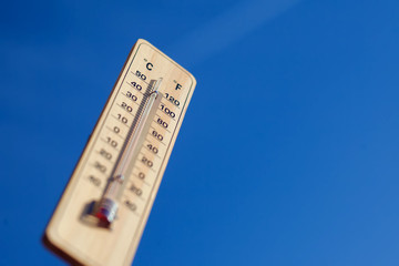 Thermometer on the blue sky background. Weather forecast and temperature concept