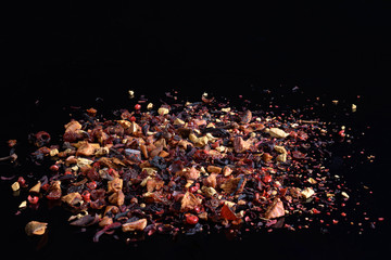 Fruit tea with dry ginger, rose hip, pink pepper, apple, cinnamon, flower petals on black background. Front view, copy space.