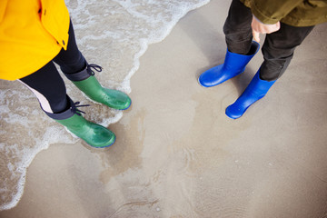 Two children standing im water of cold Baltic sea in rubber high boots