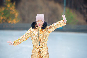 Adorable little girl skating on the ice-rink