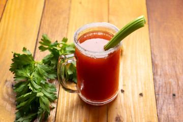 Mexican beer cocktail called michelada with celery on wooden background