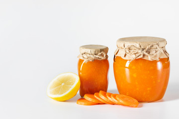 Juicy homemade carrot jam in glass jars on a white background.