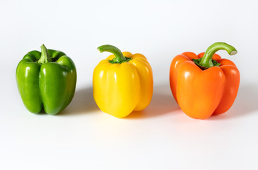 Colored bell peppers on white background. Green, yellow, orange pepper.