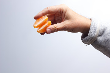 Tangerine slice in the hand of an adult person