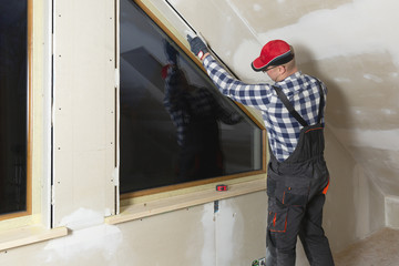 home improvement handyman installing window in new build attic by using leveler and laser leveler