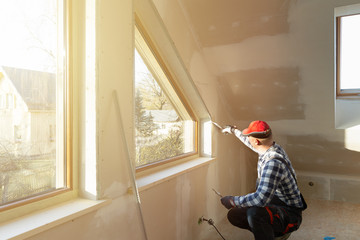 home improvement handyman filling drywall with filler in new build attic