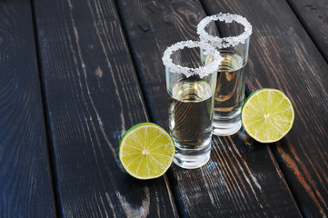 Two shots tequila with lime and salt on wooden table.Studio photography