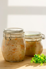 Sauerkraut in a glass jar with a bunch of parsley. Pickled cabbage on a wooden table. The best natural probiotic. Homemade kraut., Copy space for text. Vertical.