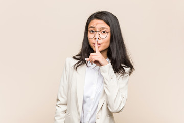 Young business chinese woman keeping a secret or asking for silence.