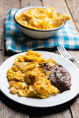 Mexican scrambled eggs with corn tortilla also called migas on wooden background