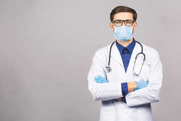 Portrait of young doctor in mask isolated on grey background.