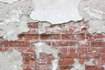 Texture of an old brick wall with fallen plaster. Background of a shabby building surface