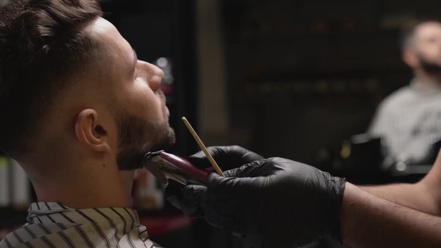 Hairdresser making beards correction with trimmer for client