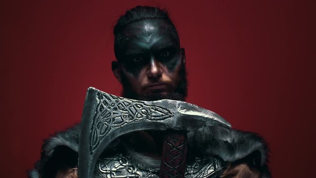 The mad look of a Viking with an axe. Portrait of a savage with an axe, opens his eyes and looks at the camera