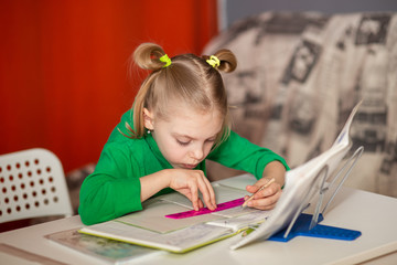 little pretty girl with poor posture, slouching, 7-8 years old, first grader, at her desk, doing homework, teaching lessons, drawing on the line
