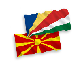 National vector fabric wave flags of Seychelles and North Macedonia isolated on white background. 1 to 2 proportion.