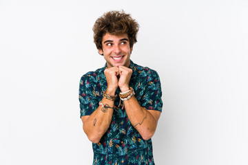 Young caucasian man wearing a flower t-shirt isolated keeps hands under chin, is looking happily aside.