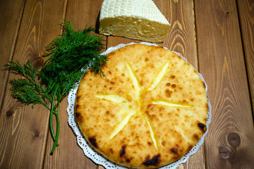Ossetian pie with cheese and dill. A traditional dish of the Caucasian fish soup. Dough product with filling on the background of an old wooden table. The concept of tasty and healthy food.