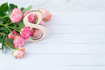 Wooden figure 8 with pink flowers on a white table. International women day. March 8